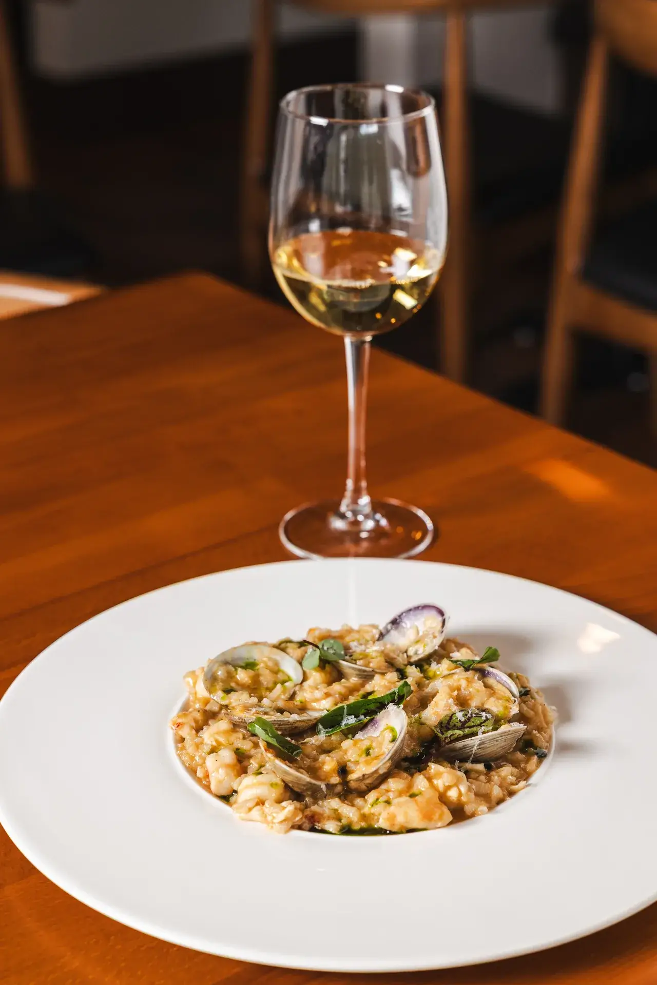A Beginner’s Guide to Italian Wine Regions 3 A glass of white wine behind Risotto ai Frutti di Mare with clams at Capriciano Osteria