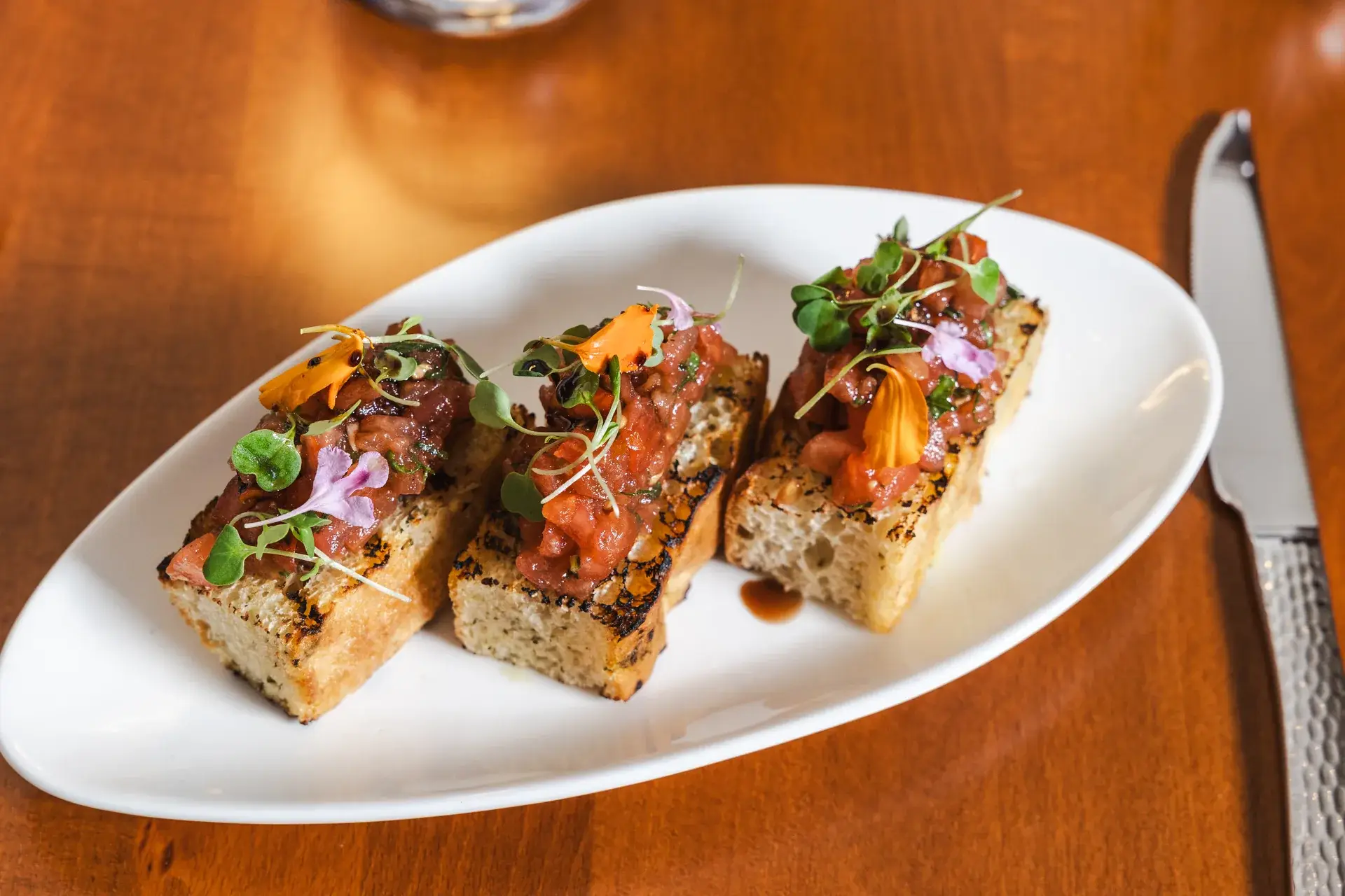 Bruschetta al Pomodoro, three toasted slices with tomato, on an oval plate at Capriciano Osteria