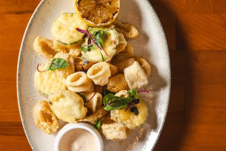 Calamari Fritti with fried zucchini, grilled lemon and aioli, seen from above at Capriciano Osteria
