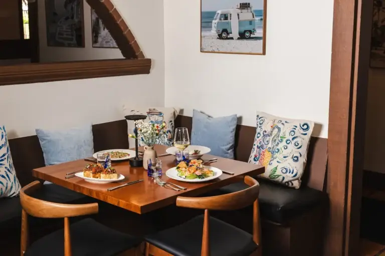 Contact 4 Corner booth with blue and patterned pillows and a set table at Capriciano Osteria in Santa Rosa