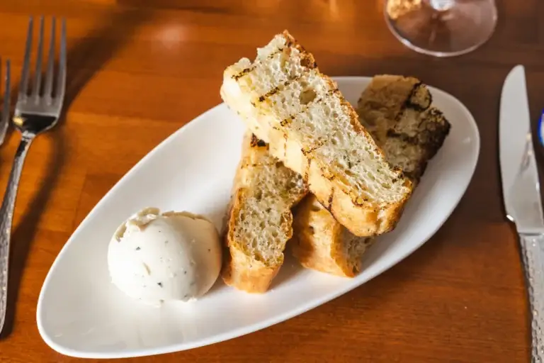 Grilled bread slices with a white spread and a glass of red wine at Capriciano Osteria