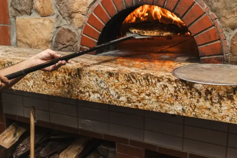 Blog 15 Hand turning a pizza with a long peel inside the flaming wood-fired oven at Capriciano Osteria