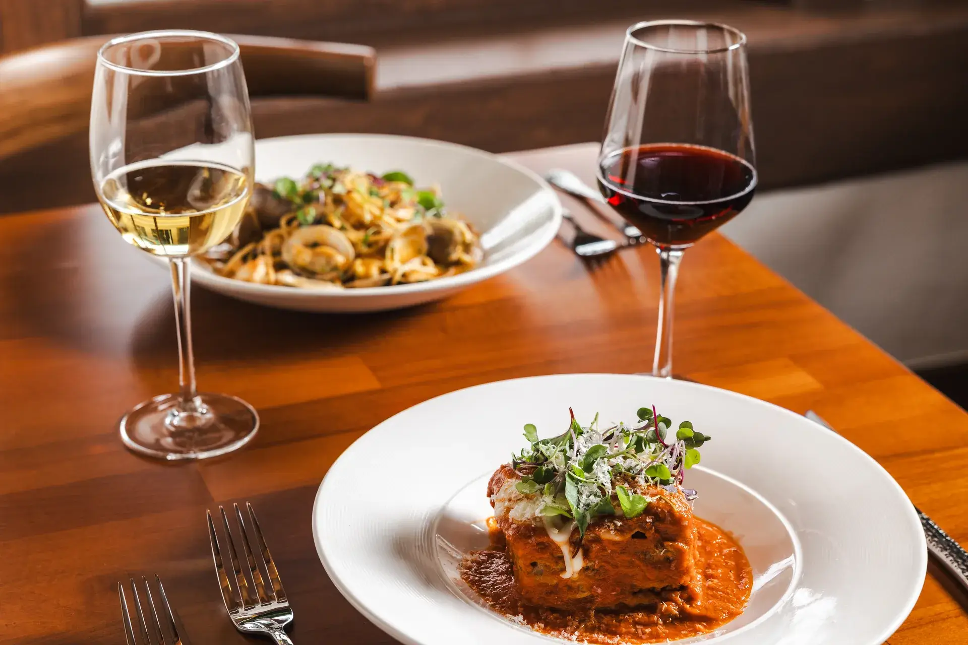 Italian and California Wines: Pairing Them With Pasta 3 Lasagna with glasses of white and red wine and spaghetti with clams behind at Capriciano Osteria