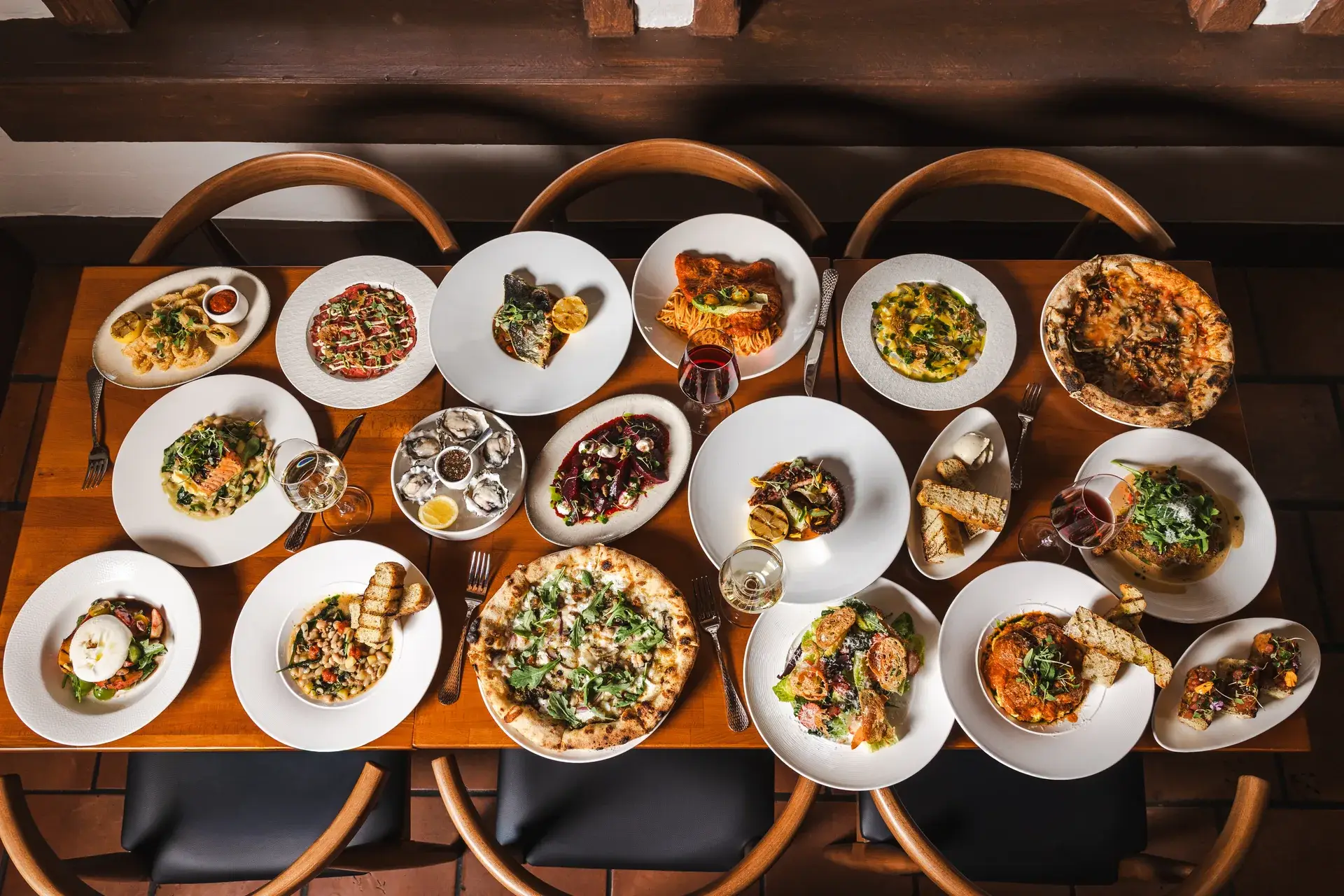 Long table of shared Italian dishes and wine ready for a group at Capriciano Osteria
