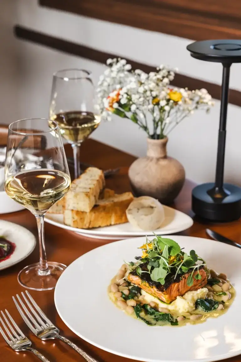 Pesce & Molluschi 3 Ora King Salmon on white beans and kale with two glasses of white wine at Capriciano Osteria