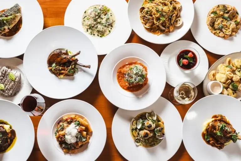 A dozen shared plates of pasta, seafood, lamb and dessert on one table at Capriciano Osteria