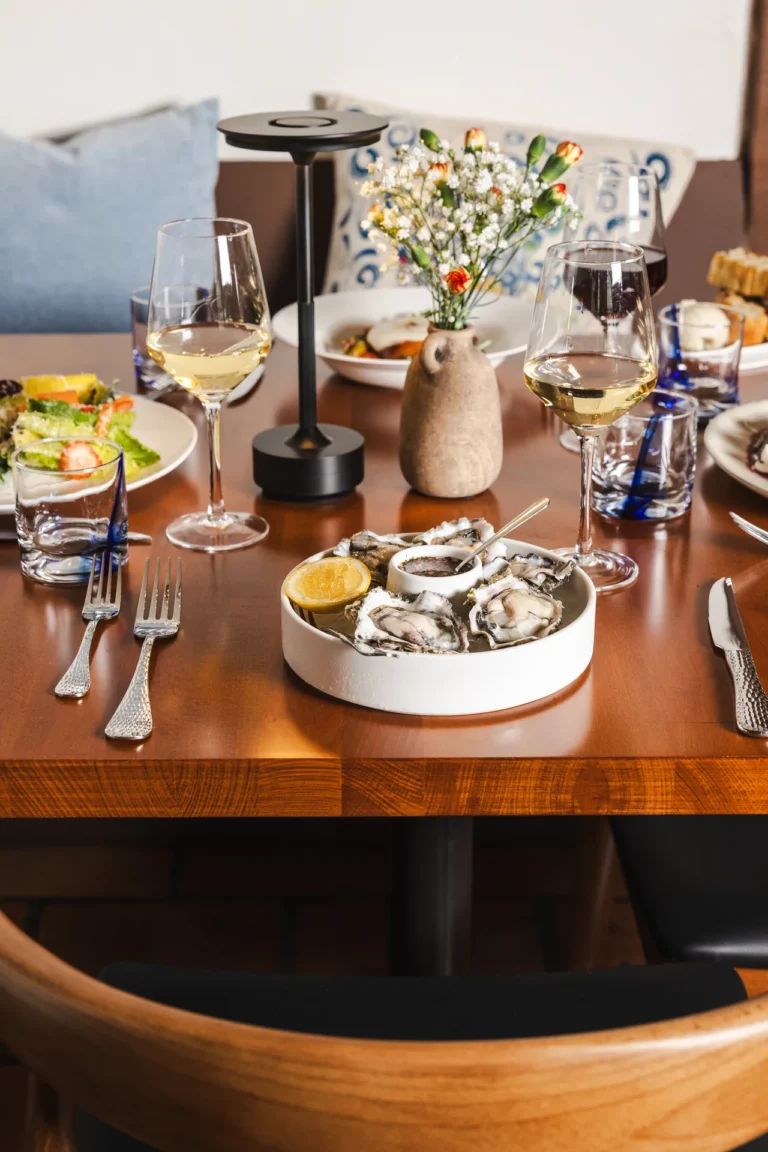 Birthdays & Milestones 2 Oyster platter on a set booth table with flowers, a table lamp and wine glasses at Capriciano Osteria