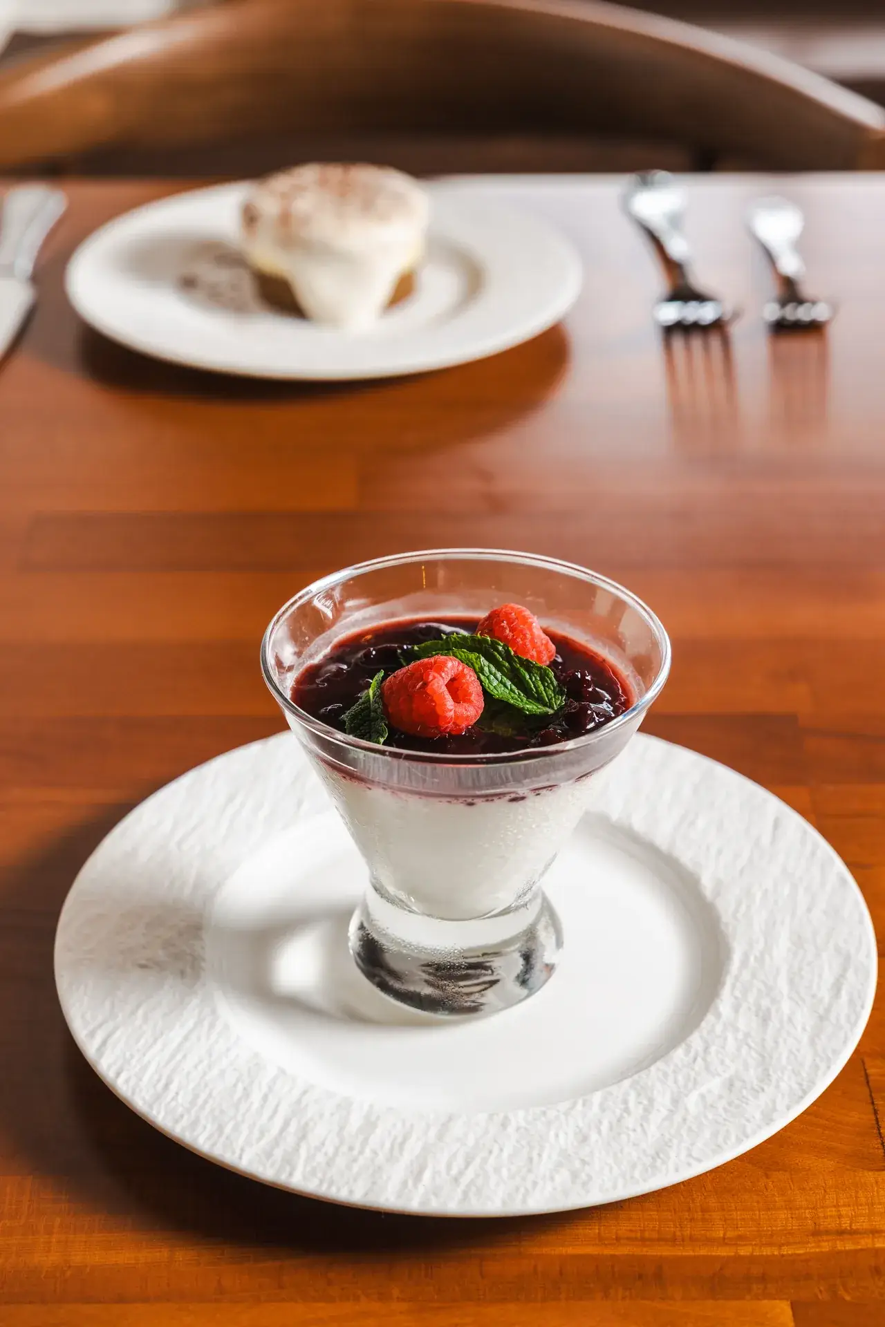 Panna Cotta with cherry compote and raspberries, a second dessert behind, at Capriciano Osteria