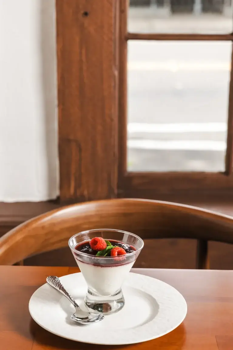 Birthdays & Milestones 3 Panna Cotta with cherry compote and raspberries on a table by the window at Capriciano Osteria