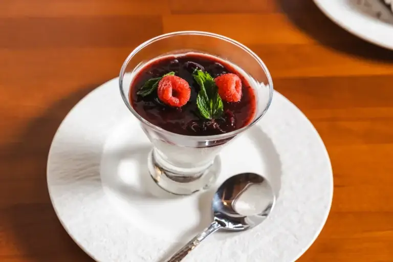 Panna Cotta with cherry compote, raspberries and mint in a glass at Capriciano Osteria