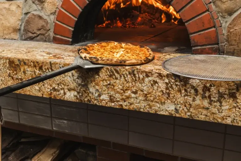 Firewood Oven Pizza 2 Pizza on a long peel coming out of the wood-fired oven at Capriciano Osteria