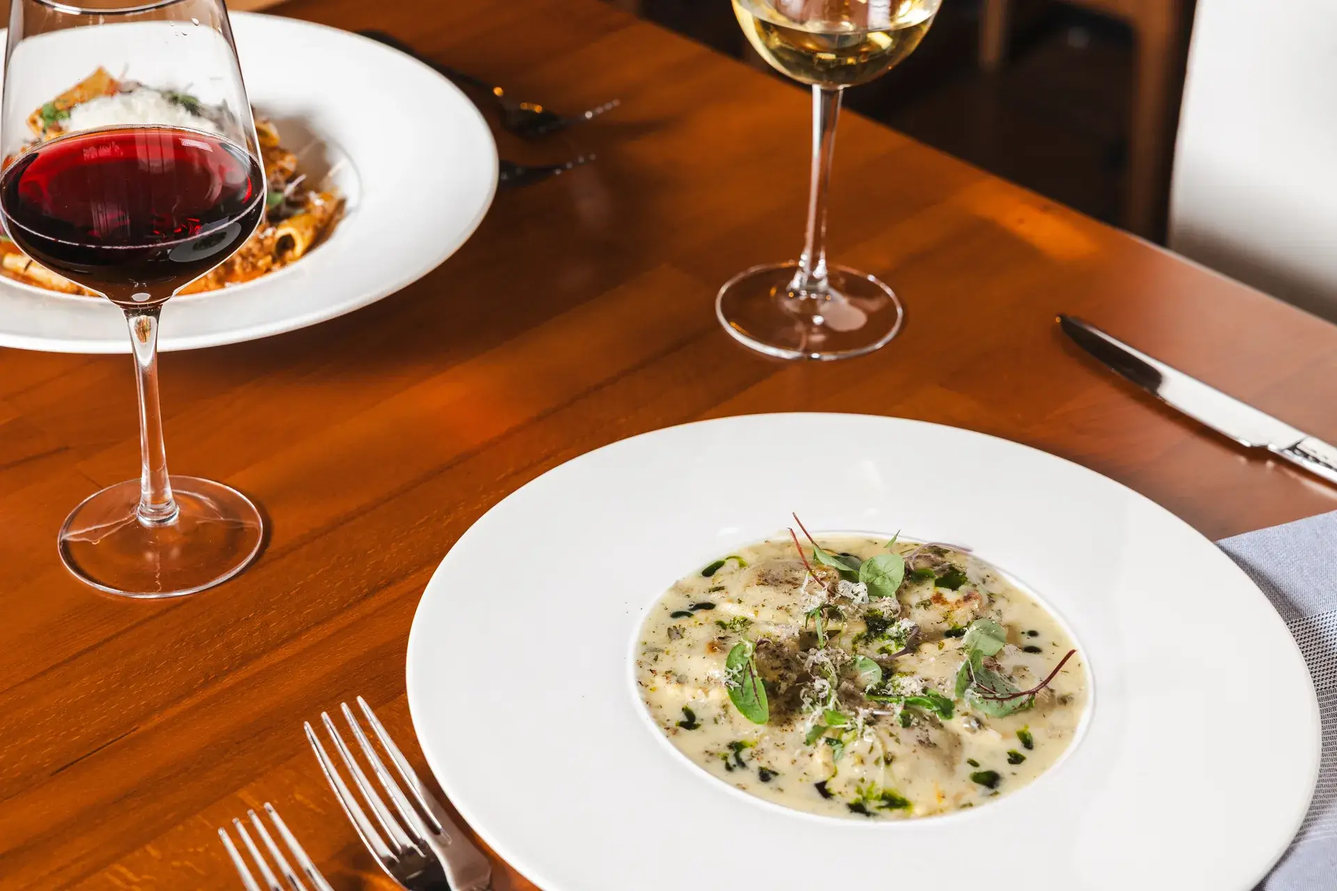 Italian and California Wines: Pairing Them With Pasta 2 Ravioli in cream sauce with glasses of red and white wine on the table at Capriciano Osteria