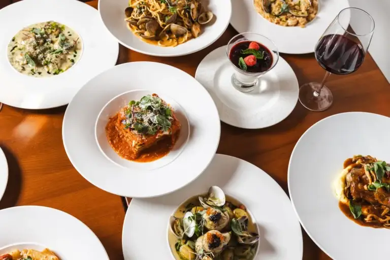 Shared plates of lasagna, clam spaghetti, risotto, ravioli and panna cotta with red wine at Capriciano Osteria