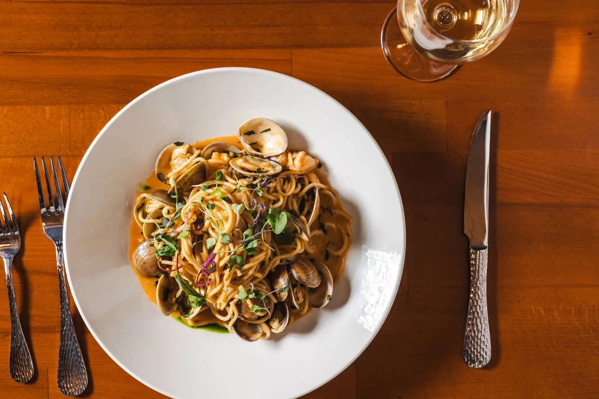 Spaghetti con Gamberi e Vongole with clams, seen from above with cutlery at Capriciano Osteria
