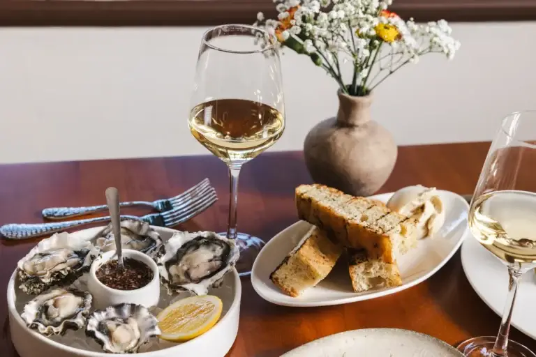 Two glasses of white wine with oysters and grilled bread, an evening of Italian dining at Capriciano Osteria