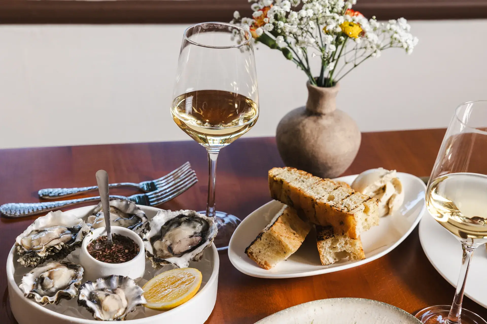 Drink Menu 1 Two glasses of white wine with oysters and grilled bread from our wine and beer menu in Santa Rosa at Capriciano Osteria